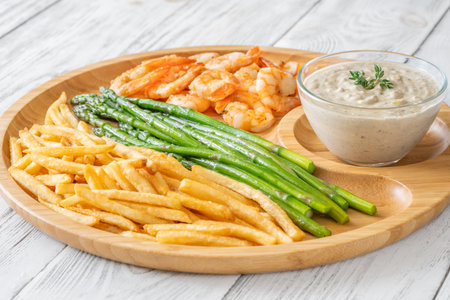 Crispy shrimp and fries balance soft asparagus and creamy sauce with thymeの写真素材