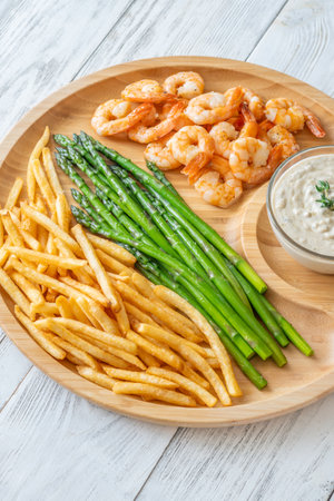 Crispy shrimp and fries balance soft asparagus and creamy sauce with thymeの写真素材