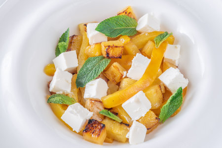 Sweet pineapple, grilled peppers, feta cubes, and mint mingle in vibrant saladの写真素材