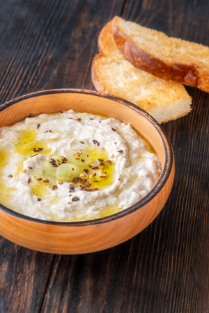 Roasted eggplant dip topped with chili flakes and oil in rustic settingの写真素材