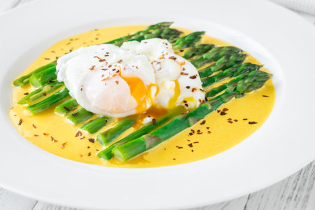 Tender asparagus spears with silky sauce and perfect poached egg on topの写真素材