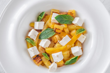 Sweet pineapple, grilled peppers, feta cubes, and mint mingle in vibrant saladの写真素材