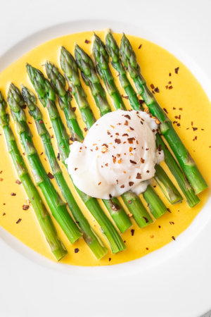 Tender asparagus spears with silky sauce and perfect poached egg on topの写真素材