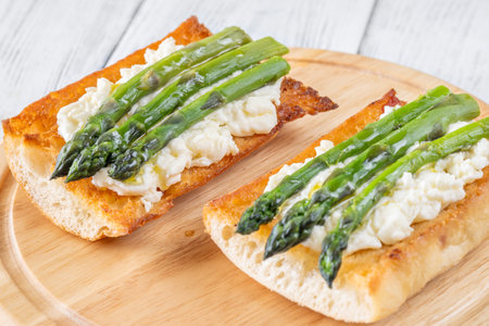 Toasted ciabatta holds creamy cheese and asparagus glistening in golden oilの写真素材