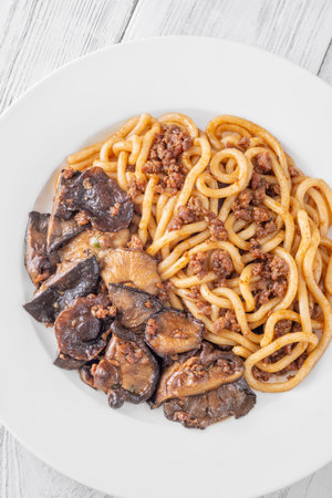 White plate of thick udon with beef, and mushroom toppingの写真素材