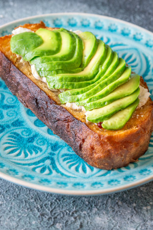 Bright avocado rests on creamy labneh, textures contrast beautifully on toasted breadの写真素材