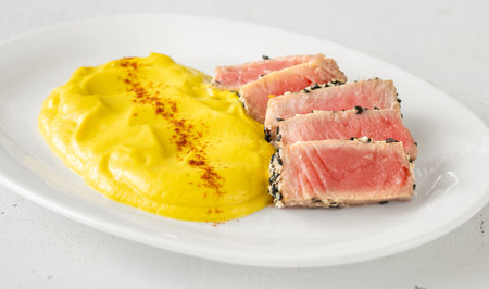 Crisp sesame tuna rests beside smooth cauliflower curry, balanced and visually refinedの写真素材