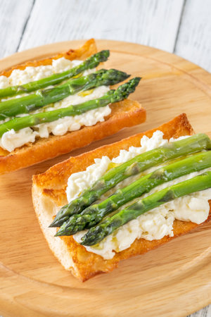 Toasted ciabatta holds creamy cheese and asparagus glistening in golden oilの写真素材