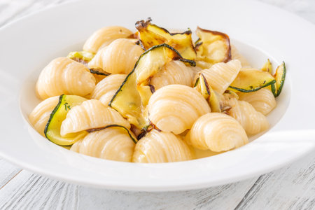 Tender conchiglioni pasta tossed with sautÃ©ed zucchini and parmesan, plated simply whiteの写真素材