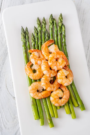 Golden shrimp add crunch and color to soft green spears of asparagusの写真素材