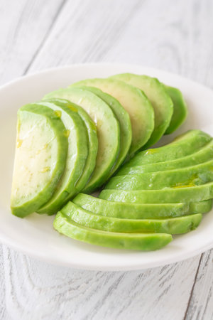 Creamy avocado slices arranged neatly in bowl, ready for topping or dipの写真素材