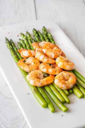 Golden shrimp add crunch and color to soft green spears of asparagusの写真素材