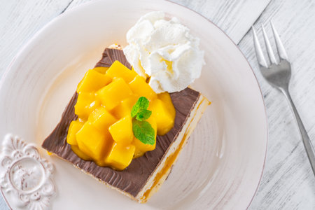 Tropical dessert square served with whipped cream, chocolate topping, and mangoの写真素材