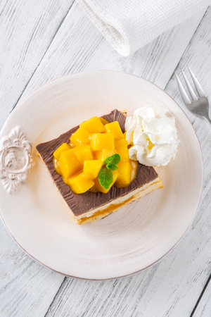 Tropical dessert square served with whipped cream, chocolate topping, and mangoの写真素材