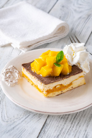 Tropical dessert square served with whipped cream, chocolate topping, and mangoの写真素材