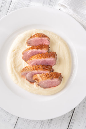 Tender duck slices with crisp skin paired beside smooth buttery mashed potatoesの写真素材