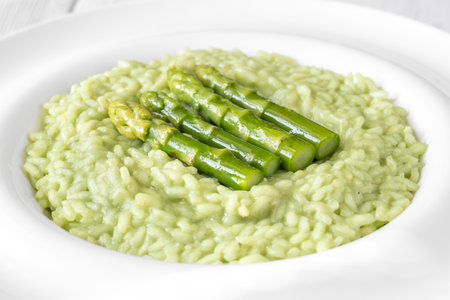 Creamy risotto with green asparagus tips, garnished and beautifully presentedの写真素材