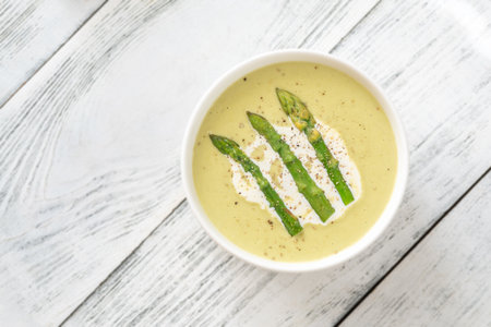 Velvety green soup topped with spears, cream swirl, and toasted breadの写真素材