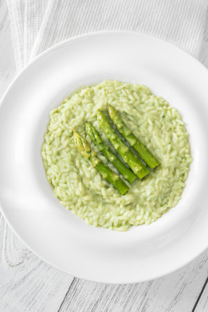 Creamy risotto with green asparagus tips, garnished and beautifully presentedの写真素材