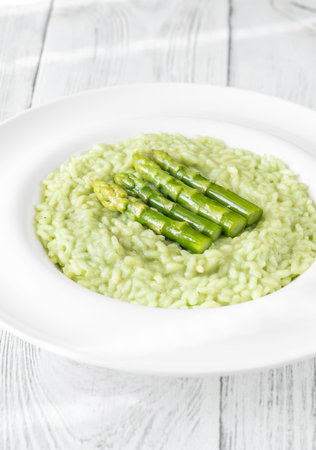 Creamy risotto with green asparagus tips, garnished and beautifully presentedの写真素材