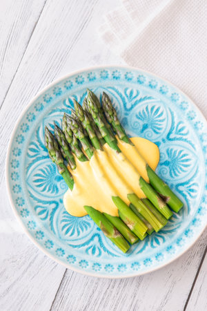 Blue Plate of Boiled Asparagus Drizzled in Silky Hollandaise Sauceの写真素材
