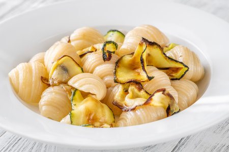 Tender conchiglioni pasta tossed with sautÃ©ed zucchini and parmesan, plated simply whiteの写真素材