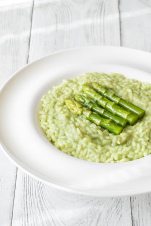 Creamy risotto with green asparagus tips, garnished and beautifully presentedの写真素材