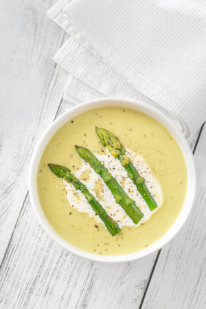 Velvety green soup topped with spears, cream swirl, and toasted breadの写真素材