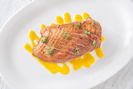 Golden fried duck breast rests atop tangy mustard lemon honey sauce baseの写真素材
