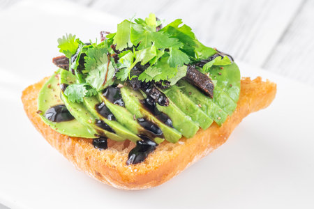 Golden toast layered with ripe avocado, tomato, cilantro and tangy balsamicの写真素材