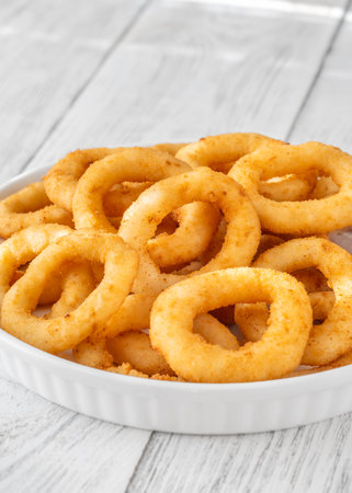 Battered onion rings paired with creamy cheese dip on rustic table settingの写真素材