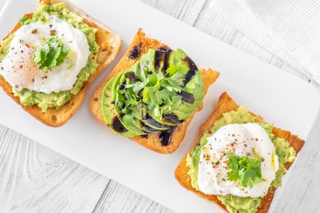 Toasted ciabatta topped with mashed avocado, egg, sundried tomato and balsamicの写真素材