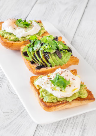 Toasted ciabatta topped with mashed avocado, egg, sundried tomato and balsamicの写真素材