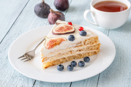 Slice cream cheese berry cake figs tea cup background inviting afternoonの写真素材