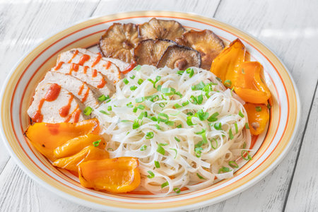 Colorful rice noodles topped with shiitake, chicken, peppers, sriracha, green onion freshness