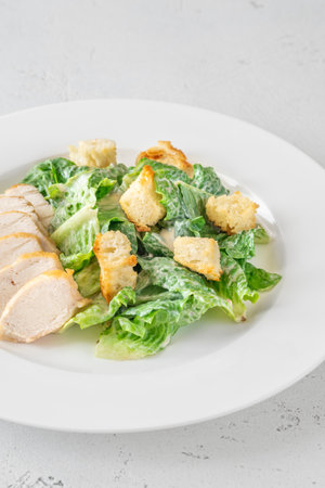 Crisp lettuce and grilled chicken blend in creamy Caesar dressing presentationの写真素材