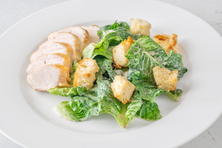 Crisp lettuce and grilled chicken blend in creamy Caesar dressing presentationの写真素材