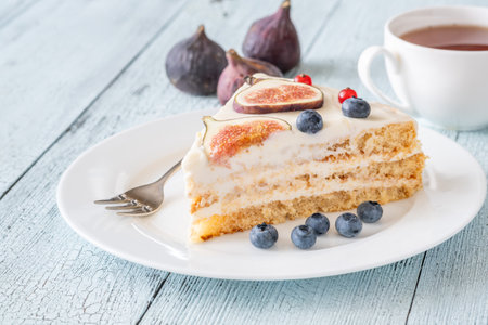Slice cream cheese berry cake figs tea cup background inviting afternoonの写真素材