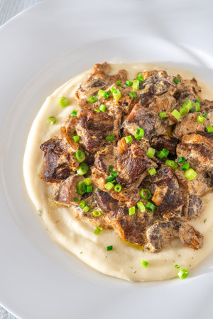 Rich, savory sauce coats seared meat and mushrooms resting on smooth herb-flecked pureeの写真素材