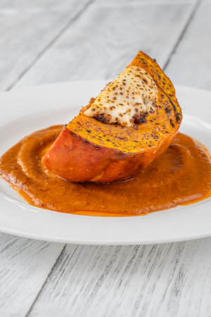 Savory portion of stuffed Hokkaido pumpkin topped with mozzarella, rich tomato sauceの写真素材