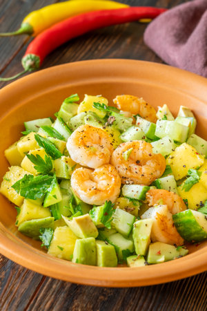 Colorful salad with shrimp, mango, avocado, cucumber, brightened by lemon olive sauceの写真素材