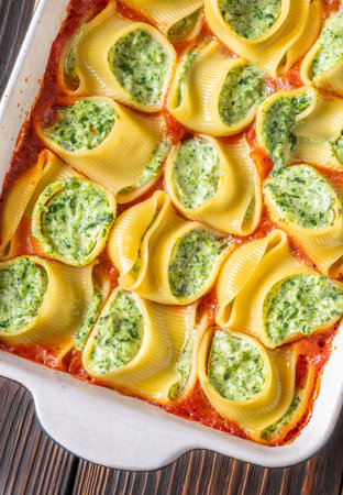 Stuffed pasta shells nestled in bubbling tomato sauce, baked until golden and perfectly tenderの写真素材