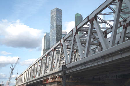 A span of a railway bridge under construction against the background of Moscow City skyscrapersの写真素材