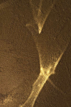 Reflected sun glare on a golden rough painted wall, abstraction, backgroundの写真素材