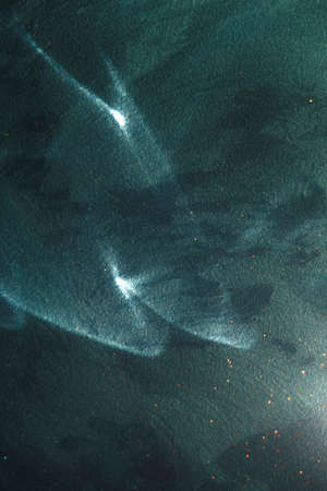 Reflected sun glare in the form of two bright centers on a blue rough painted wall, abstraction, backgroundの写真素材