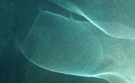 Reflected round sun flare on a blue rough painted wall, abstraction, backgroundの写真素材