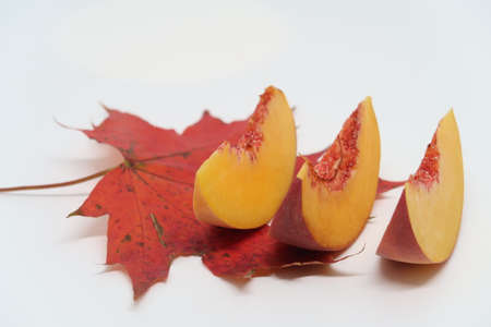 Three peach slices lie on a red maple leaf, autumnの写真素材