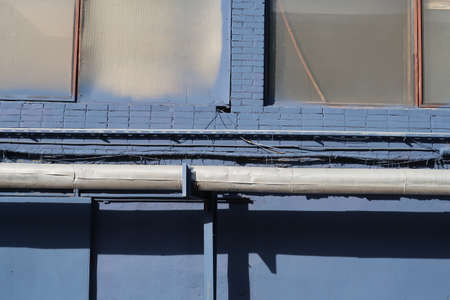 Heat pipes on a blue brick wall under the windowsの写真素材