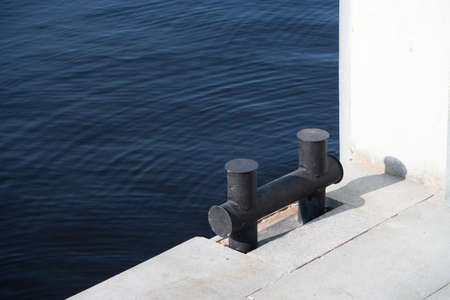 Double mooring bollard against a blue water surface