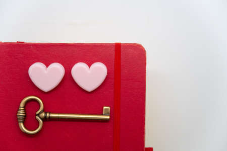 Two paper clips in the shape of pink hearts and a key on an old weekly, memories, moodの写真素材